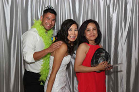 Group of 3 people at a wedding in front of a silver backdrop