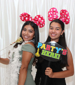2 girls posing using props in the photo booth