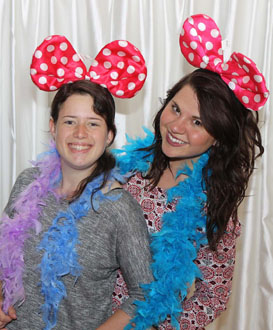two girls posing at a school event in the photo booth with a white backdrop